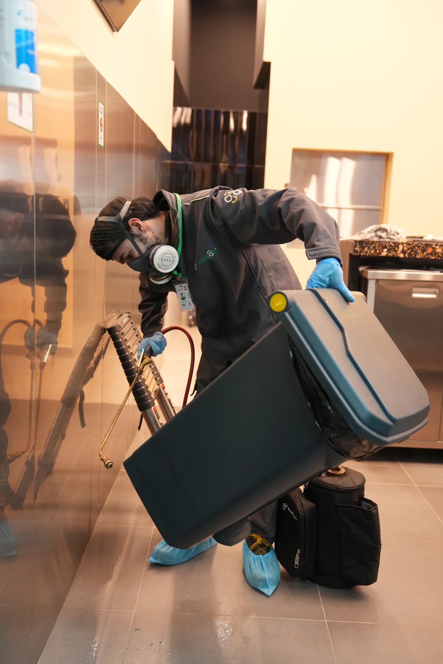 GreenLab technician servicing a pest control device in an indoor commercial setting.